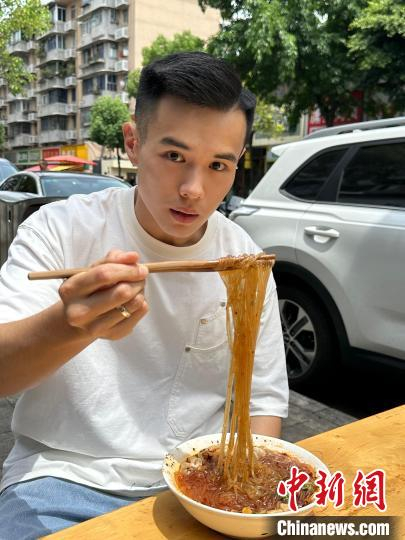 图为此前杨寓棠在成都街边品尝肥肠粉。受访者供图