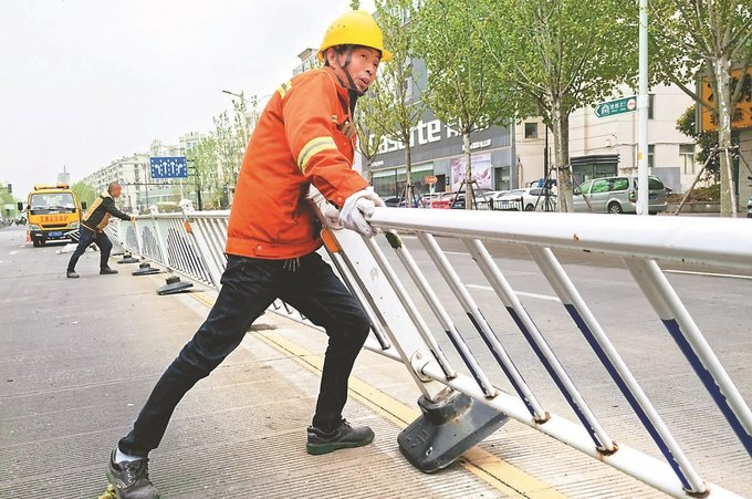 4月12日，工人在南通市崇川区钟秀西路扶正被大风吹倒的隔离护栏。 许丛军 摄 （视觉江苏网供图）
