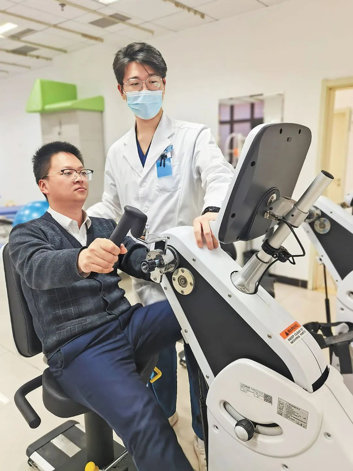 王源洋（右）为患者进行康复治疗。人民日报记者 李硕 摄