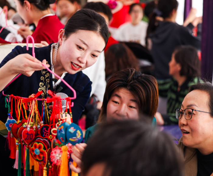 图为列车工作人员向旅客展示列车非遗作品。通讯员 李磊 摄
