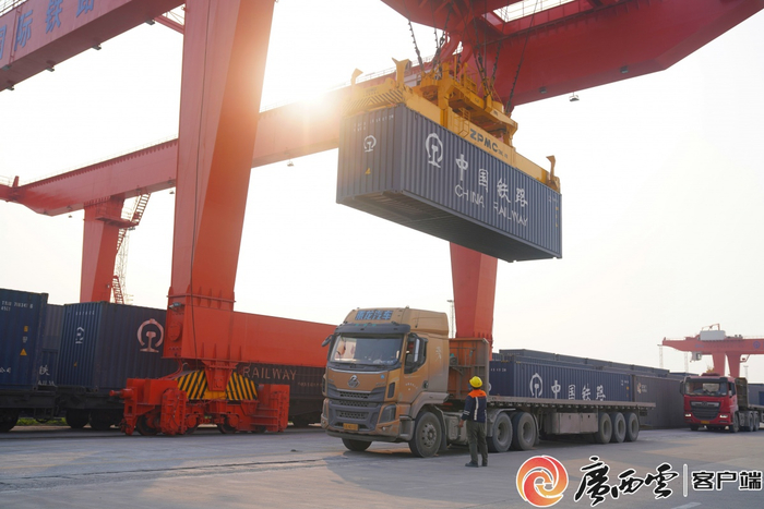 装卸作业班组指挥门吊将集装箱从汽车上卸下，吊装上火车。陈星宇 摄