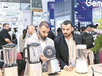 图为境外采购商在广交会展区挑选产品。 本报记者 薛鹏 摄