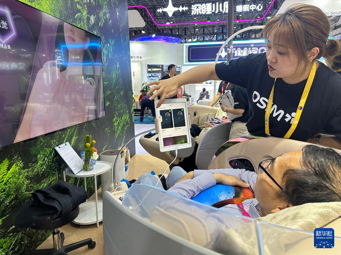 工作人员正在为体验者介绍智能按摩椅使用步骤。新华社记者 陈凯姿 摄