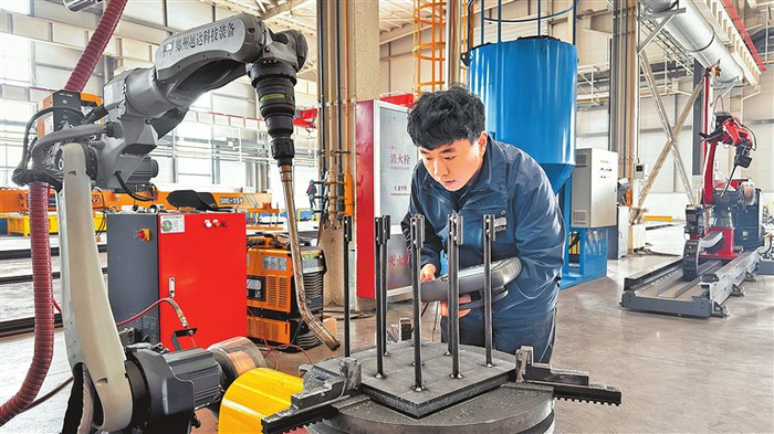 工业机器人机械工程师刘召亮，在工业机器人组装车间操作设备。