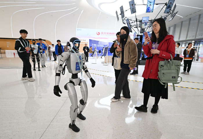 　　  2025年3月26日，北京中关村国际创新中心的一款正在行走的宇树G1机器人吸引人们拍照留影。新华社记者 陈钟昊 摄