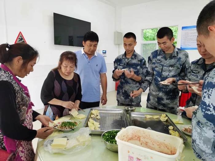 张兴会（左一）与驻军部队官兵一起包饺子。
