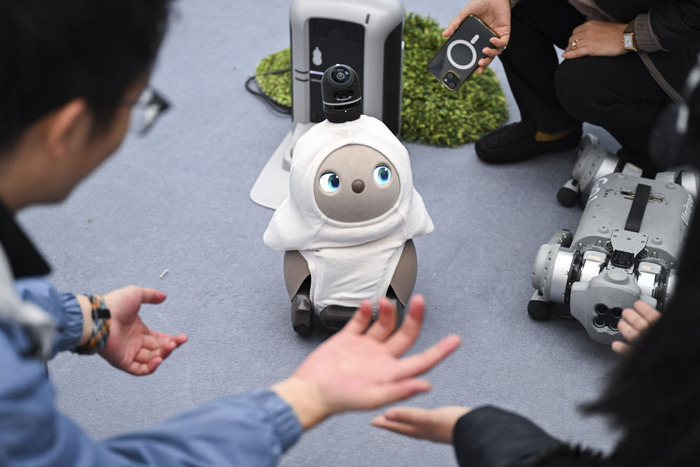 2月21日，观众在上海举行的2025全球开发者先锋大会现场与陪伴机器人互动。新华社发（陈浩明 摄）