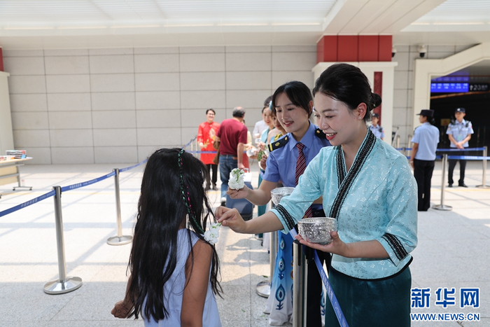 4月12日，中老铁路磨憨站，铁路工作人员为旅客送上泼水祝福。新华网发（陈畅 摄）