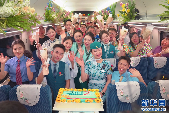 4月12日，D87次国际旅客列车上，工作人员与旅客欢庆中老铁路国际旅客列车开行两周年。新华网发（周涛 摄）