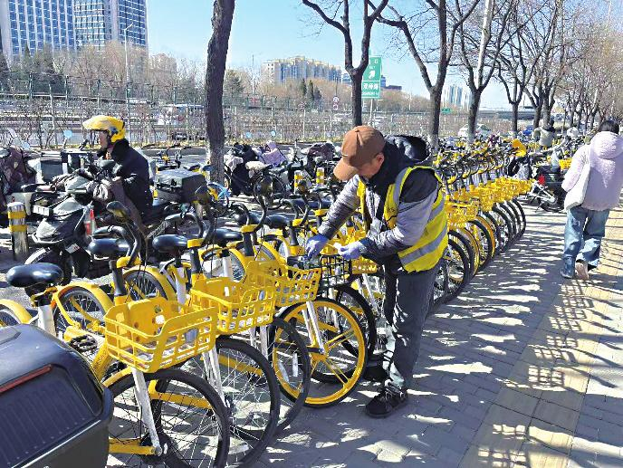 　　美团单车运维团队在清理车身小广告。（受访单位供图）    