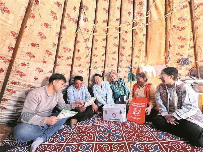     六师北塔山牧场草建连党支部副书记、连管会连长堂阿塔尔（左一）在牧区宣传防疫知识（摄于3月20日）。热孜贝克·麦吾勒太  摄