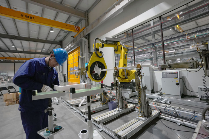 　　  2月26日，在哈尔滨电机厂有限责任公司线圈分厂智能制造车间，工人与智能设备在进行协同加工生产作业。新华社记者 王松 摄