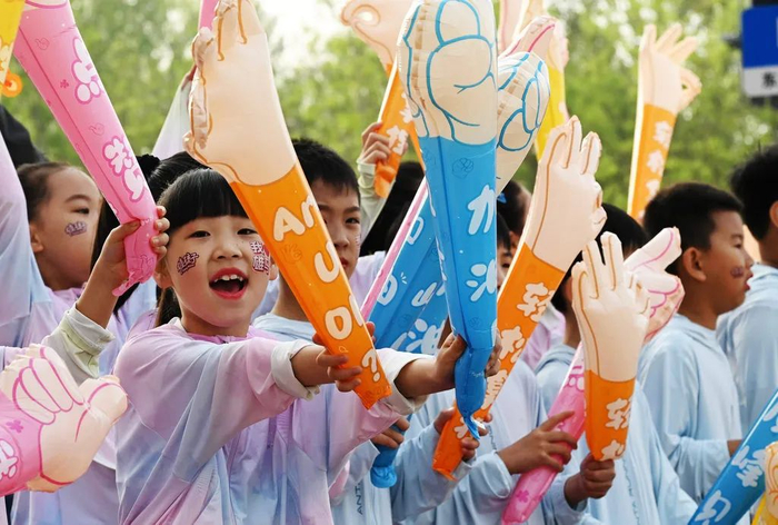 4月20日，2025雄安马拉松鸣枪开跑。赛道外，一群“雄孩子”为跑者加油。河北日报客户端记者 刘光昱 摄