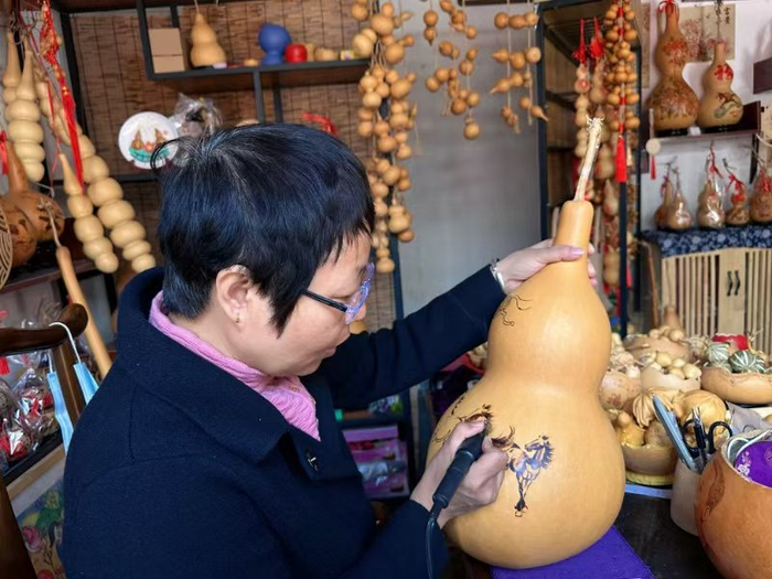 忻州古城葫芦烙画店铺内，李云珍正在创作《八骏图》。人民网记者 麻潞摄