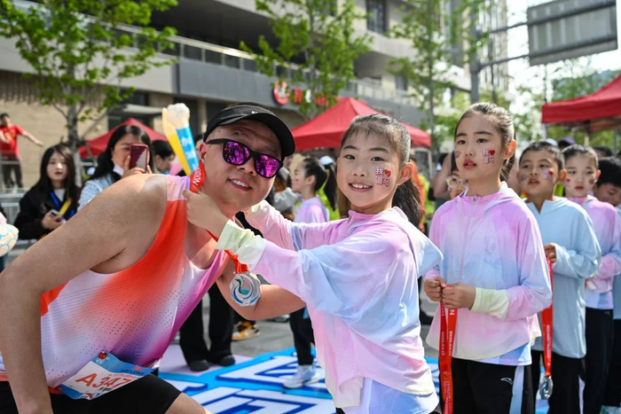 “雄孩子”为跑者戴上奖牌。雄安媒体中心王伟倩 摄