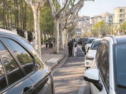 家长在东环龙路停车时避开收费的智慧停车位，而是贴着划设停车位的外沿白线停放。毛锦伟 摄