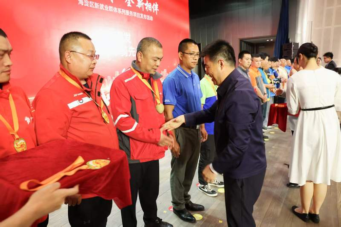 嘉宾为新就业群体代表颁发“车骑先锋”徽章及助力包。新京报记者 浦峰 摄