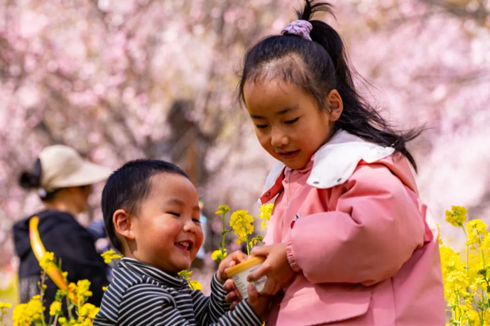 小朋友在桃树下开心玩耍。人民日报记者 徐驭尧 摄