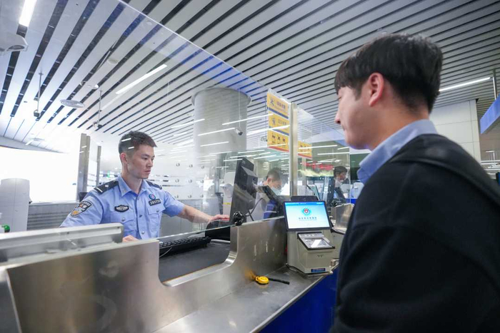 白云边检站移民管理警察为出入境旅客高效办理通关手续。（资料图片）