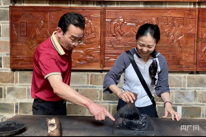 黄行忠（左）指导游客体验雕版印刷（央广网记者  罗晓英  摄）