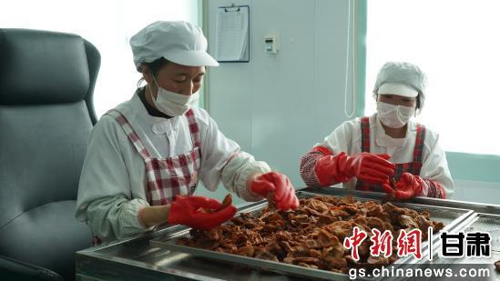 　　图为工人师傅正在按大小分拣苹果果干。