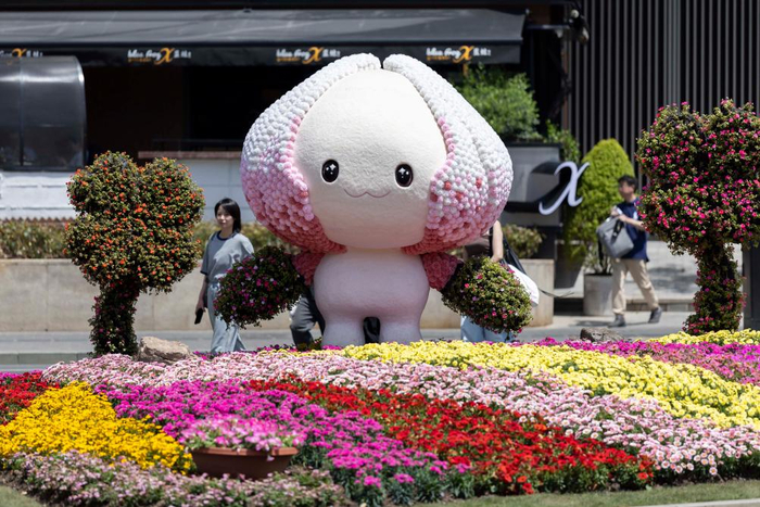 4月18日，在上海国际花展黄浦新天地主会场，人们从今年花展吉祥物“花宝宝”附近经过。新华社记者王翔 摄