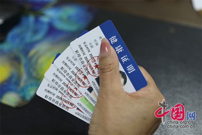 龙子湖区曹山街道卫生服务中心工作人员展示所办理出的健康证。