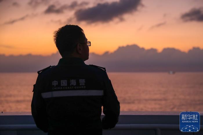   ↑3月25日，在黄岩岛附近海域，一名海警执法员在高栏舰上观赏晚霞。
