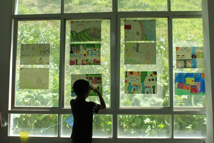 　　小朋友正在帮忙布置美丽田野画于窗户  团队成员拍摄