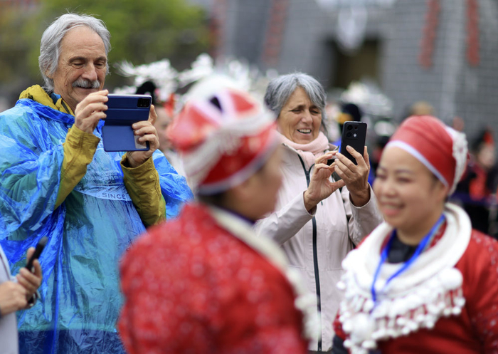 　　  4月12日，外国游客在贵州省黔东南苗族侗族自治州台江县举行的“苗族姊妹节”庆祝活动上拍摄。新华社记者刘续 摄