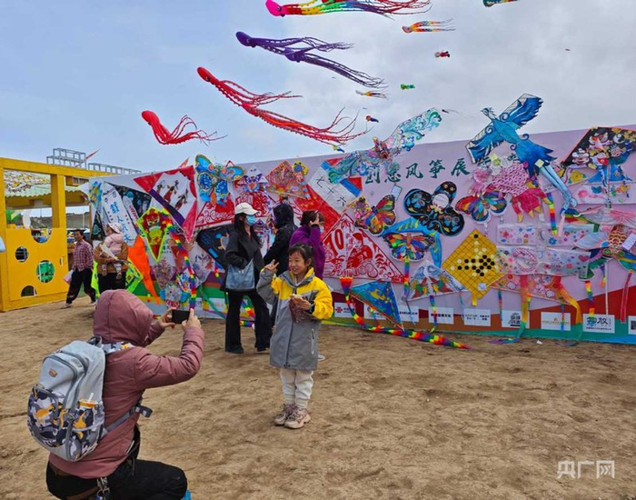 游客与风筝合影  （央广网记者郭璁悦  摄）