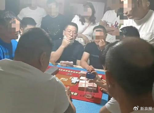 汤恕与人聚众赌博的视频截图，坐在中间戴着眼镜的抽烟男子为汤恕。 视频截图