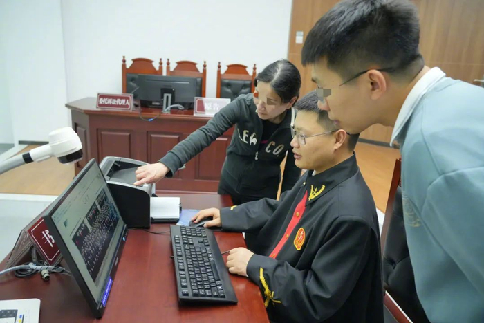 图为庭审中，廖大姐向重庆市璧山区人民法院法官张永（中）指出多年前公司员工合影中自己的位置。刘茂涵 摄