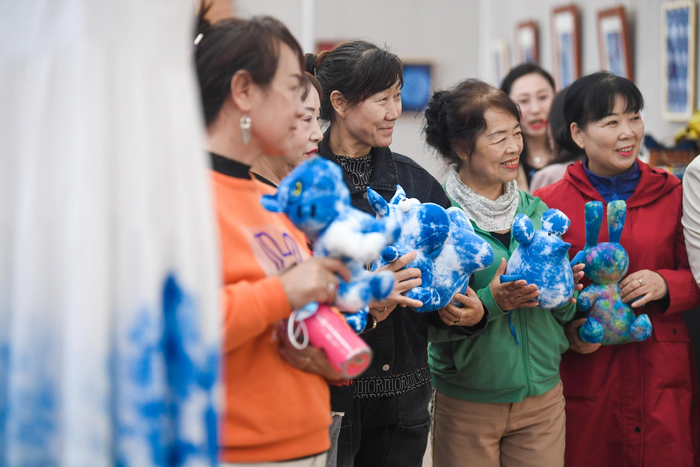 参观市民拿起精致的布偶拍照留念。