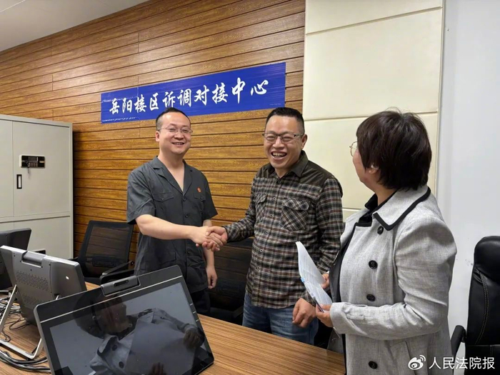 图为农民工代表握住湖南省岳阳市岳阳楼区人民法院法官刘界（左）的手，脸上写满感激，向他表达深深的谢意。杨子旋 摄