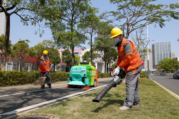 2025年3月19日，在深圳市坪山区石井街道，环卫机器人与环卫工人进行协同作业。新华社记者 毛思倩 摄