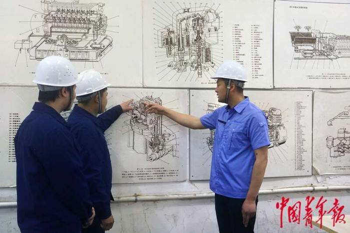 李维（右）向年轻人讲解图纸。中青报·中青网记者 王海涵/摄