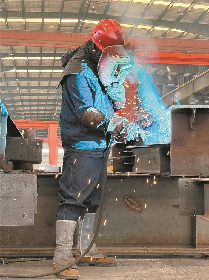     4月22日，在兵团新型建材经济技术开发区，新疆三合万宏钢构环保科技有限责任公司工人在焊接钢板。    张海茜  摄