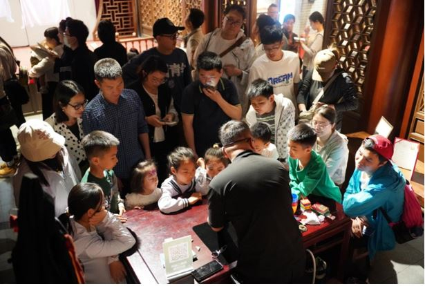 　　“古彩戏法”传承人现场教学，引发小观众热情围观，传统民间技艺在沉浸互动中焕发新生机。（主办方供图）