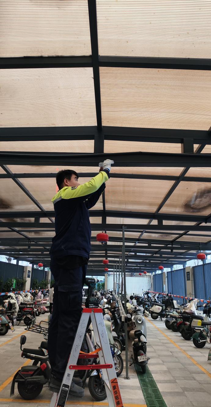图为:万科物业在管小区的电瓶车棚正在加装智能烟雾传感器
