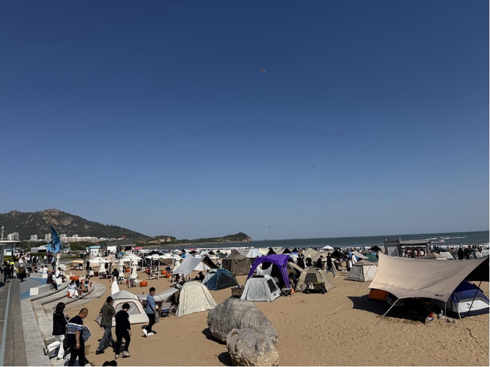 石老人海水浴场，游客铺满沙滩（财联社记者摄）