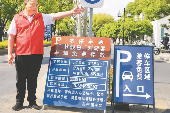 5月1日，苏州市356家机关企事业单位内部停车场免费开放。图为身着红马甲的志愿者正在引导汽车通行。 陈弋 摄