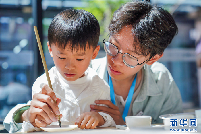   5月2日，在泉州工艺美术职业学院展区内，小游客体验瓷艺勾线作业。新华网 肖和勇 摄