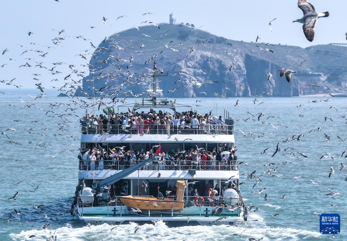 5月3日，游人在山东省荣成市海驴岛乘船进行环岛游（无人机照片）。