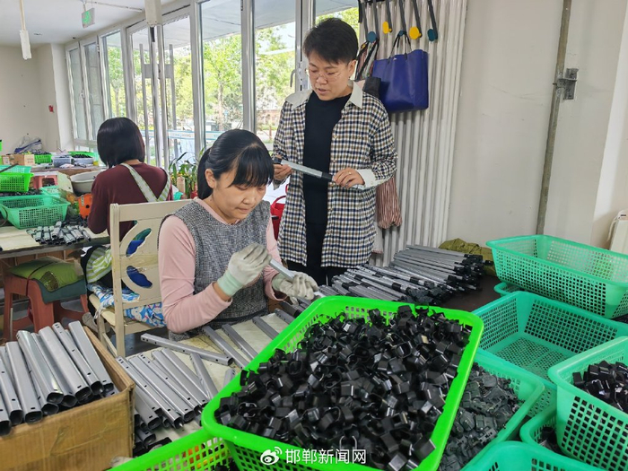 图为”雄业创工坊”运营负责人王桃烨（右一）在箱包车间巡查。雄安媒体中心 李连成 摄
