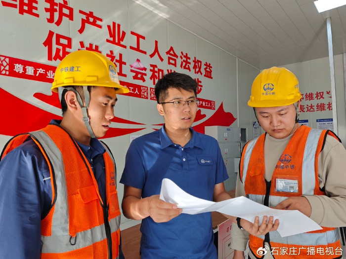 卓孔越（中）正在与工友讨论建设进展。本报记者 李如意摄