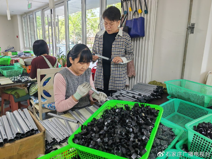 图为”雄业创工坊”运营负责人王桃烨（右一）在箱包车间巡查。雄安媒体中心 李连成 摄