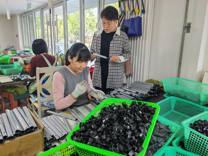 图为”雄业创工坊”运营负责人王桃烨（右一）在箱包车间巡查。雄安媒体中心 李连成 摄