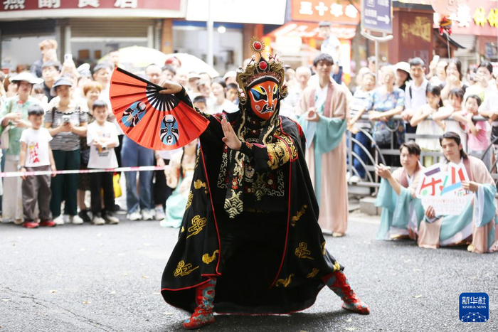 5月3日，游客在四川省乐山市特色文化街观看川剧变脸表演。
