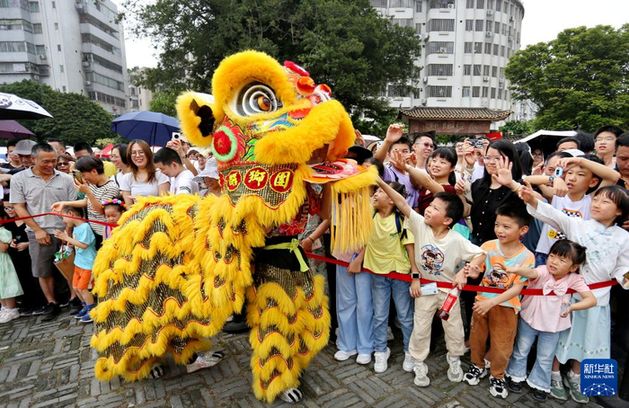 5月2日，游客在广东省佛山市禅城区南风古灶旅游休闲街区与佛山醒狮互动。